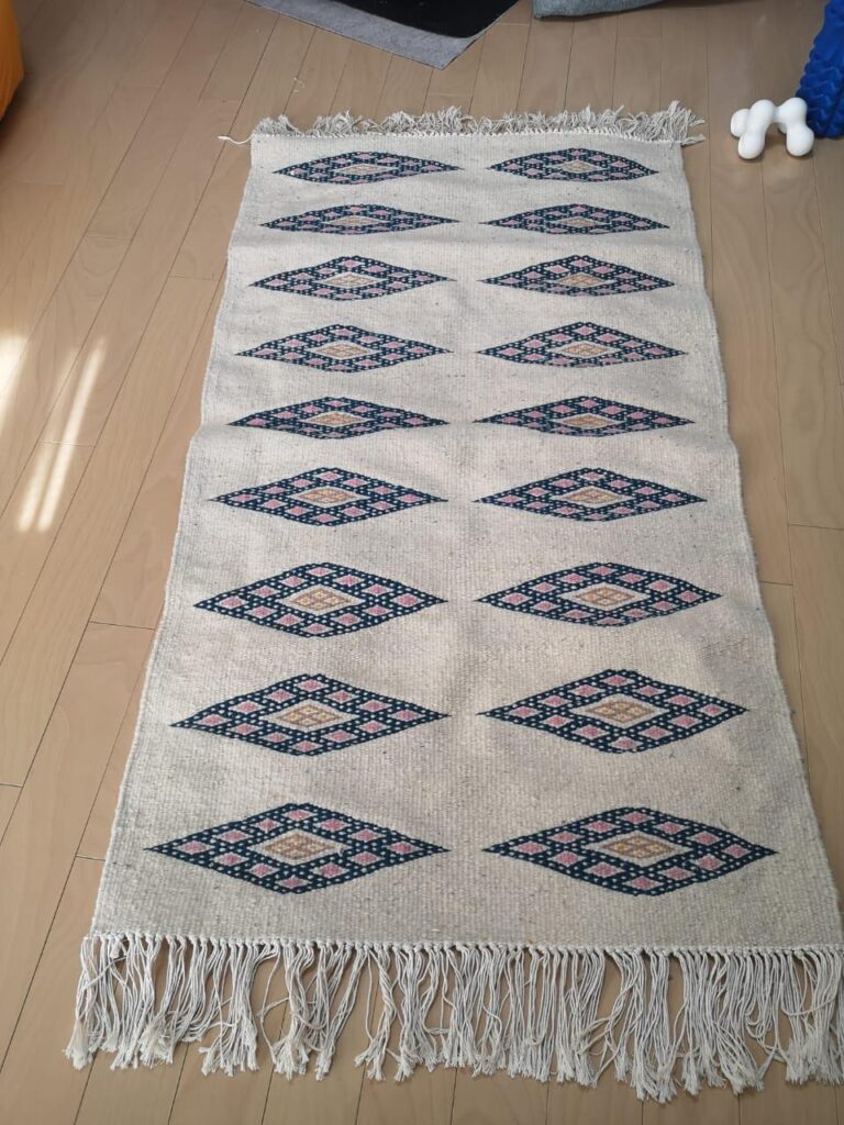 Decorative rug with diamond patterns and fringes.