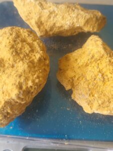 Three yellowish rocks on a blue surface.